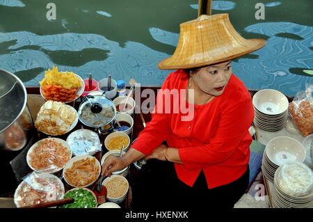 Damnoen Saduak, Thailand - 9. Januar 2010: Frau im Strohhut verkaufen köstlichen thailändische Speisen an Bord ihr Kanalboot an der Damnoen Saduak Floating Mar Stockfoto