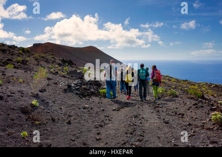 Touristen Wandern entlang eines Pfades auf eine geführte Tour in der Region der Cumbre Vieja in Fuencaliente, La Palma.  Die Landschaft ist das Lava-Gestein von den Vulkanen im Bereich erstellt.  Sehr wenig Vegetation ist in der Lage, auf diesem Barron Land wachsen. Stockfoto