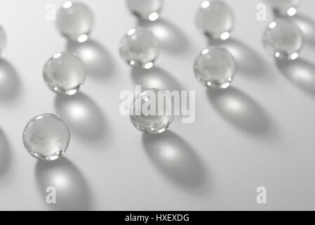 Farbloses Glasmurmeln auf einer weißen Fläche in Licht getaucht Stockfoto