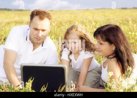 Familie mit Laptop auf der Wiese Stockfoto