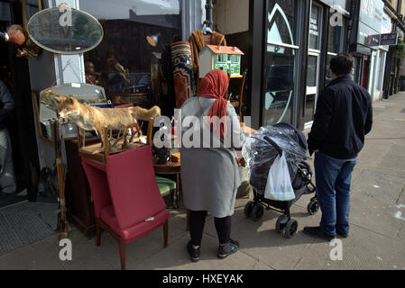 Asiatische Familie Flüchtling gekleidet Hijab Schal auf Straße in der UK alltägliche Szene Trödelladen oder Antiquitätengeschäft Fuchs