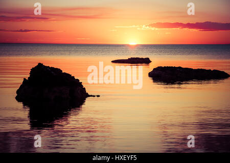 Sonnenuntergang über dem Wasser, mit Rock-Silhouetten Stockfoto