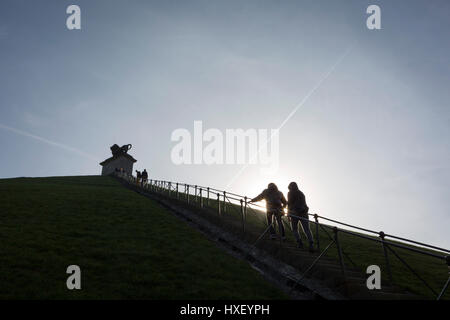 Besucher klettern und steigen den steilen Gradienten von 225 Stufen, 43 Meter hohen Waterloo Lion Schlachtfeld Mound, am 25. März 2017, an Waterloo, Belgien. Den Löwenhügel (Butte du Lion ist ein großer konische künstliche Hügel, die im Jahre 1826 abgeschlossen. Es erinnert an die Lage auf dem Schlachtfeld von Waterloo, wo eine Muskete Kugel traf die Schulter von William II der Niederlande (Oranien) und schlug ihn von seinem Pferd während der Schlacht. Vom Gipfel bietet des Hügels eine 360-Grad-Aussicht auf das Schlachtfeld. Die Schlacht von Waterloo wurde 18. Juni 1815 gekämpft. Eine französische Armee unter Napoleon Bonaparte w Stockfoto