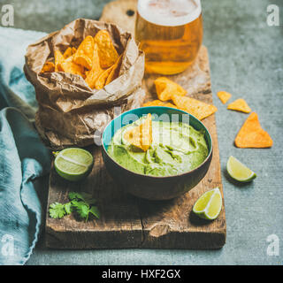 Frische Guacamole Sauce in blauen Keramikschale, Mais-Chips, Bier Stockfoto