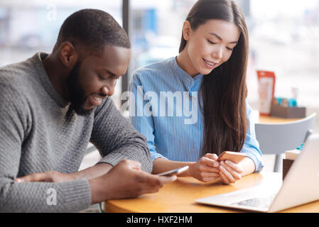 Junger Mann und Frau mit Smartphones im café Stockfoto
