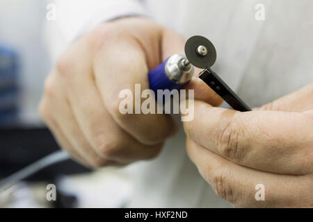 Reparatur von Sonnenbrillen mit Schneidwerkzeug Nahaufnahme von Händen Stockfoto