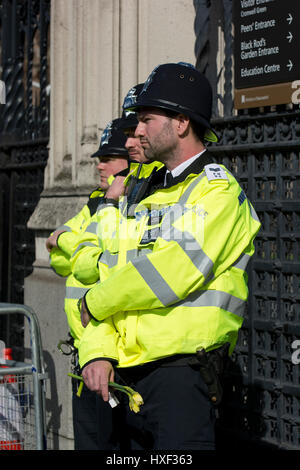 Polizist hält Blumen am Tor zu den Westminster-Palast nach Westminster Terroranschlag in London, Vereinigtes Königreich. Stockfoto