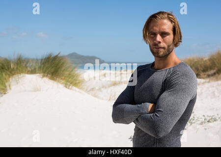 Porträt von zuversichtlich Sportler am Strand gegen Himmel stehen Stockfoto