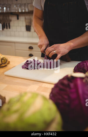 Mittelteil des männlichen Chef schneiden Rotkohl auf Schneidebrett in Großküchen Stockfoto