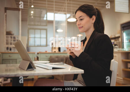 Geschäftsfrau Kaffeetrinken beim Betrachten von digitalen Tablet im café Stockfoto