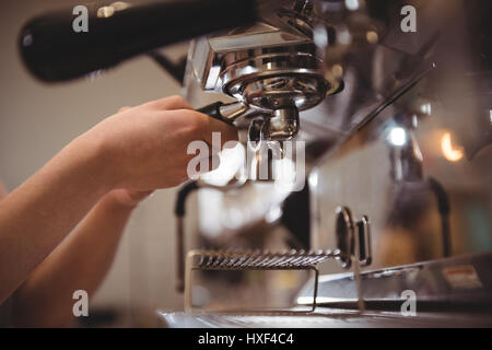 Nahaufnahme des weiblichen Befestigung Siebträger in Kaffeemaschine im Café barista Stockfoto