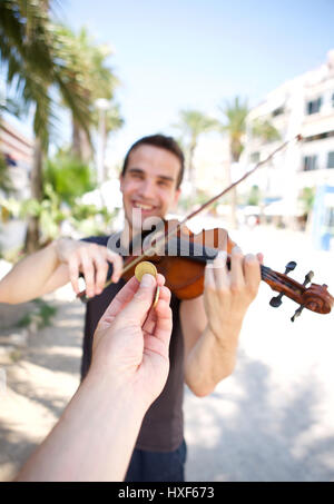 Hand bezahlen Busker Mann Geigenspiel außerhalb Stockfoto