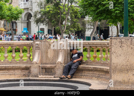 Ein Mann, der auf der Marmorbank im historischen Zentrum schläft. Lima, Peru. Stockfoto