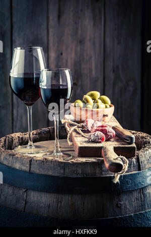 Leckeren Wein im Glas mit Wurst und Oliven auf Holzbrett Stockfoto