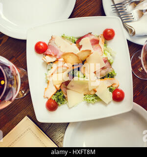 Draufsicht auf Cäsarsalat auf weißen Teller im Restaurant serviert. Menühintergrund Stockfoto