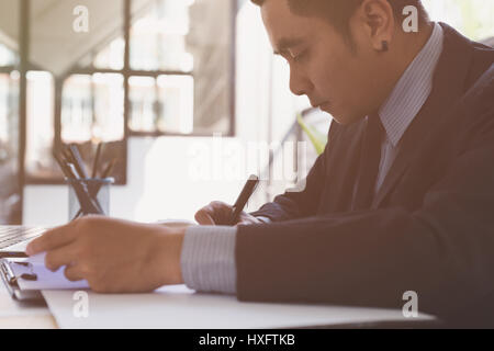 Geschäftsmann im Anzug Unterzeichnung oder Schreiben eines Dokuments auf ein weißes Blatt Papier mit einem Füllfederhalter Stockfoto