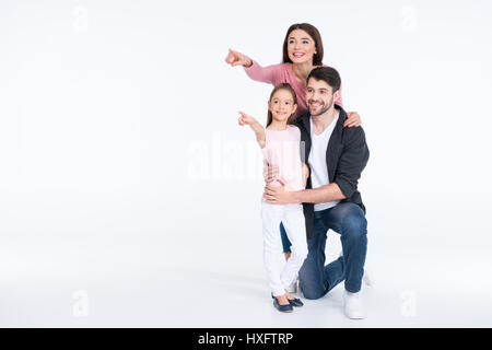 Glückliche junge Familie zusammenstehen und zeigen mit Fingern auf weiß Stockfoto