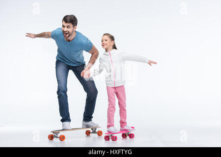 lächelnd, Vater und Tochter reiten Skateboards auf weiß Stockfoto