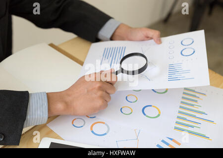 Business Analytics und Statistiken. Geschäftsmann Studienbericht mit Hilfe einer Lupe. Stockfoto