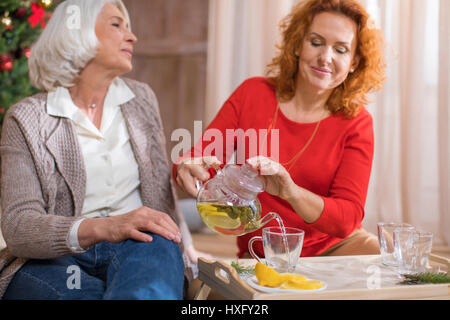 Zwei Reife Frauen Tee mit Zitrone im Glas Tassen gießen Stockfoto