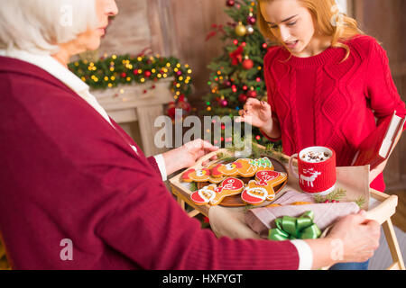 Reife Frau mit Tablett mit Weihnachtsgebäck für ihre Enkelin Stockfoto
