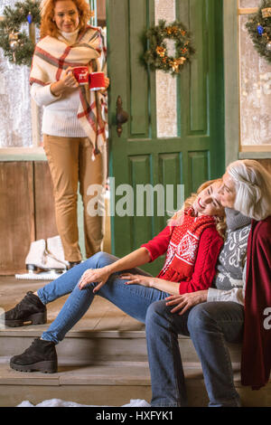 Lächelnden Großmutter und Enkelin sitzt auf der Treppe und umarmt Stockfoto