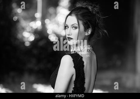 Mädchen mit langen Haaren trug ein schwarzes Kleid, alte Kirche stand Stockfoto