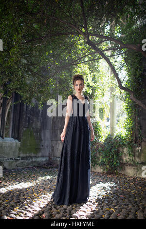 Mädchen trug ein schwarzes Kleid, alte Kirche stand Stockfoto