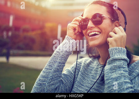 Glückliche junge Frau Musik hören mit Kopfhörern bei Sonnenuntergang im freien Stockfoto