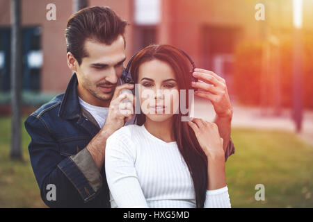 Junges Paar Musik hören im Freien bei Sonnenuntergang Stockfoto