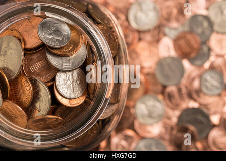 Münze Jar - eine Draufsicht auf eine Münze Glas mit Münzen in den Hintergrund. Stockfoto