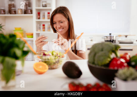 Schöne junge Frau nehmen Foto von gesunder Salat mit Smartphone für ihr Blog. Stockfoto