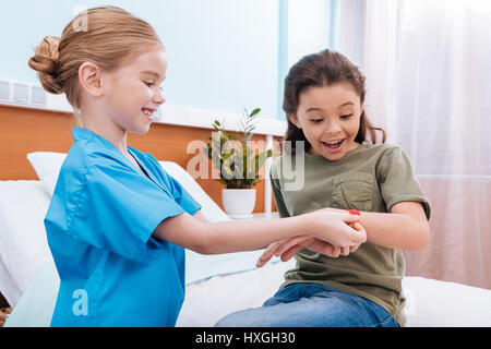 lächelnde Mädchen Krankenschwester aufgeregt Patienten Arm im Krankenhaus Kammer Putz aufsetzen Stockfoto