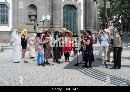 Ein Musiker in einem Multi-farbigen Mantel spielt in einer Straße Band in Funchal Stockfoto