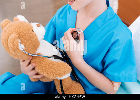 Teilansicht des Mädchen Krankenschwester hörende Herzschlag mit Teddybär als Arzt Stockfoto