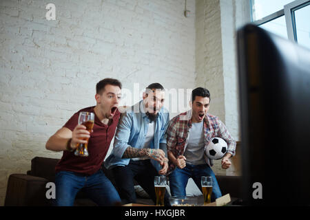 Porträt von drei emotionalen Erwachsene Männer beobachten Sport im Fernsehen und jubeln vor Aufregung beim Aufstehen und schreien mit Bier passen Stockfoto