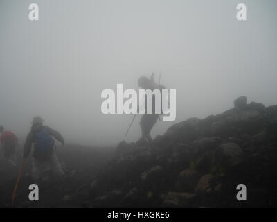 Gruppe von Touristen Wanderungen, den Berg hinunter und hinauf auf den Berg in der Cloud durch den Dunst und Nebel, hoch in Höhe Stockfoto