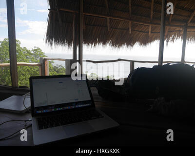 Surfen im Internet mit einem Macbook in einem schönen Resort mit einem Strand vor dem Hotel Stockfoto