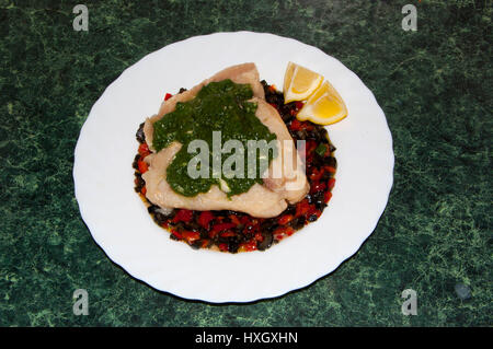 Fischfilet in Milch mit einer Beilage von Oliven und Paprika-Sauce und Spinat gekocht Stockfoto