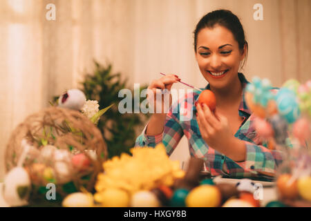 Wunderschöne lächelnde junge Frau Malerei Osterei zu Hause. Stockfoto