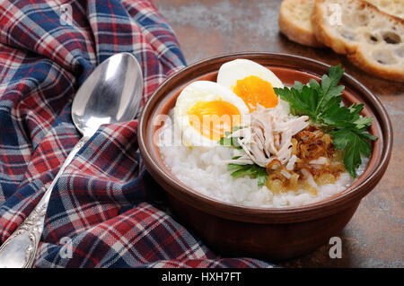 Reis Brei Ingwer Congee mit Ei, Huhn, knusprigen Schalotten und Petersilie Stockfoto