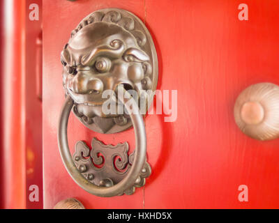 Chinesischer Löwenkopf Türklopfer an rote Tür Stockfoto