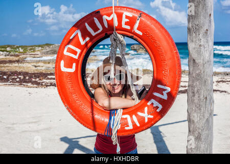 Junge Frau sucht Trog roten Reifen Schaukel am Strand von Cozumel in Mexiko Stockfoto