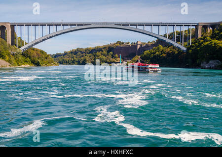 Die Hornblower Boot, Niagara Wonder, voll mit Touristen neben dem kanadischen Wasserfälle und Rainbow Bridge in Niagara, Ontario, Kanada. Stockfoto