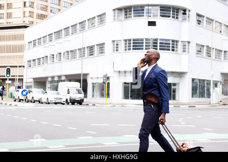 Erfolgreicher afrikanischer Geschäftsmann mit Tasche unterwegs und telefonieren mit Handy Stockfoto