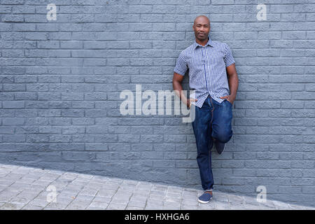 Voller Länge Porträt eines entspannten afroamerikanische Wand gelehnt Stockfoto