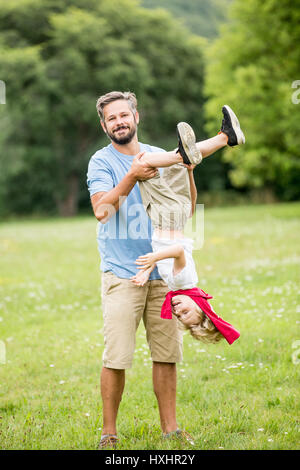 Vater und Sohn spielen Roughouse im Park im Sommer Stockfoto