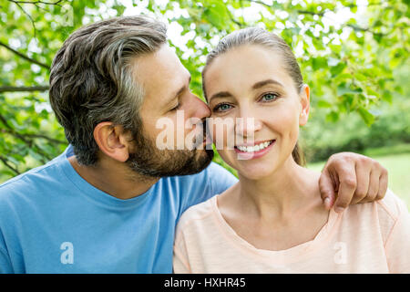 Mann küsst Frau mit Liebe als ein glückliches Paar im Sommer in der Natur Stockfoto