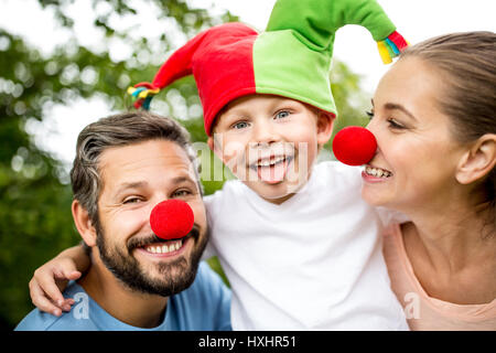 Fröhlicher Junge mit Narr Mütze mit Eltern im Karneval Stockfoto