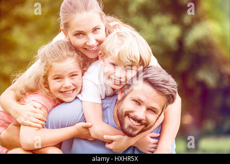 Glückliche Familie mit zwei Kindern in Harmonie in der Natur umarmt Stockfoto